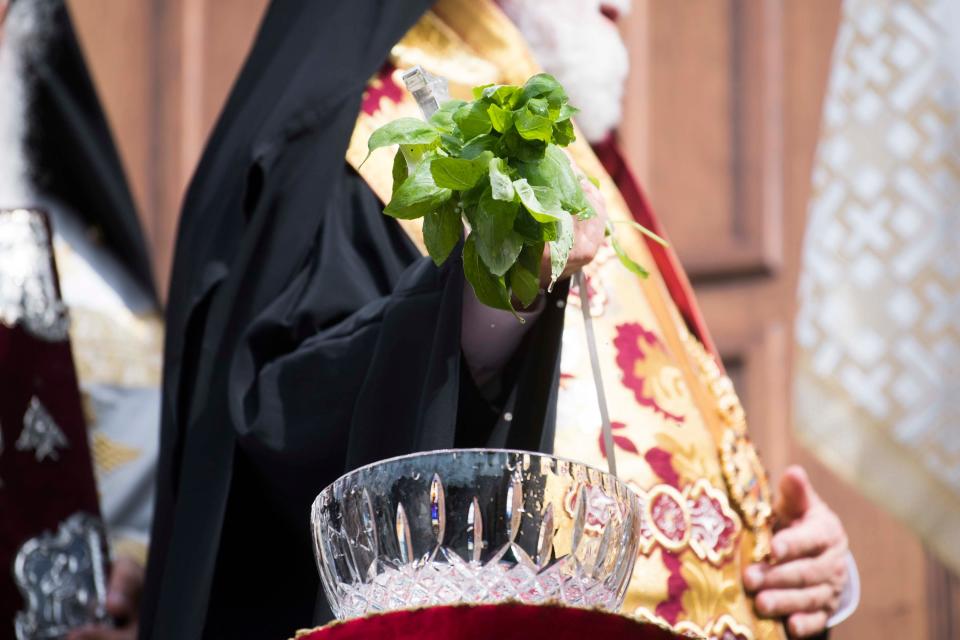 Archbishop Alexios, who oversees U.S. Southeast Greek Orthodox churches, dips basil leaves into holy water to bless the church at the door-opening event of St. George Greek Orthodox Church at 4070 Kingston Pike in Knoxville on June 8, 2019, four years after a fire devastated the church.