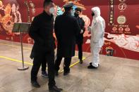 A worker in a protective suit speaks with staff members at the Wangfujing subway station, as the country is hit by an outbreak of the new coronavirus, in Beijing