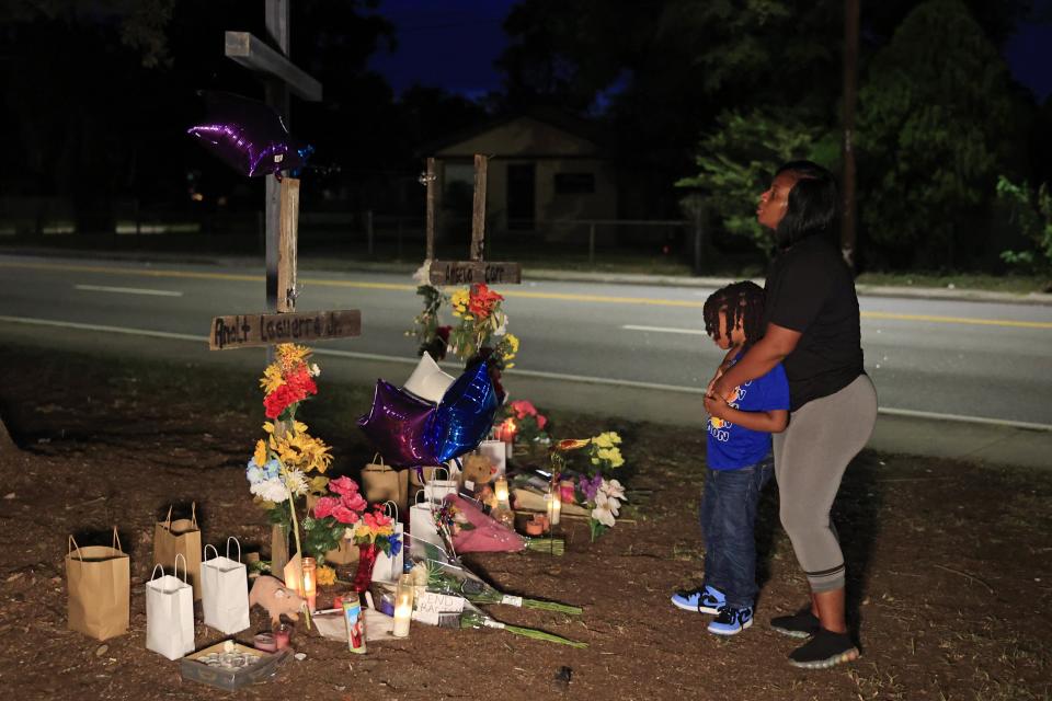 People pay their respects on Aug. 28 at a memorial constructed with crosses and a mural at Almeda Street and Kings Road in Jacksonville, Fla. Two days earlier a white gunman shot and killed three targeted Black victims at the Dollar General store about a block away in what's been classified a hate crime.