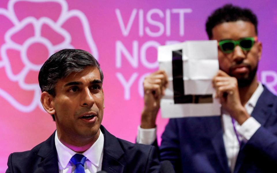 Independent candidate Niko Omilana holds an "L" behind Britain's Prime Minister Rishi Sunak who speaks after winning his seat in the general election at the Richmond and Northallerton