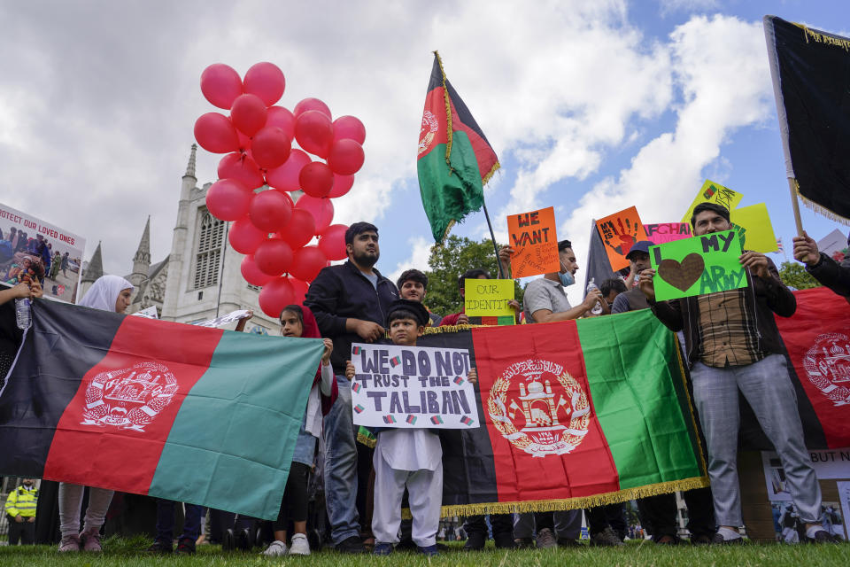 Demonstrators hold Afghanistan flags, during a protest in Parliament Square, London, Wednesday, Aug. 18, 2021. Britain’s government says it plans to take in 5,000 Afghan refugees this year, especially women and children, in response to the Taliban's seizure of power. Officials provided details about the resettlement program on Wednesday as lawmakers held a heated emergency debate on developments in Afghanistan. (AP Photo/Alberto Pezzali)