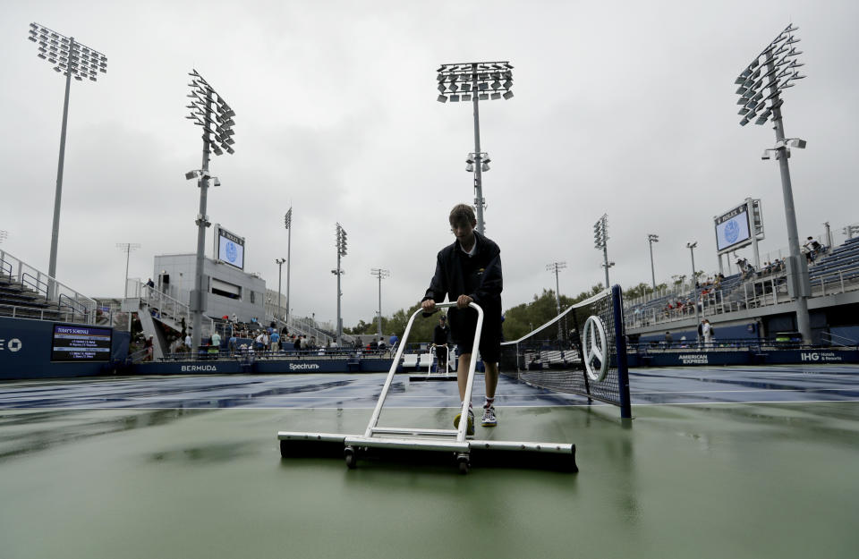 A court attendant clears water off court 6 during a rain delay of the second round of the US Open tennis championships Wednesday, Aug. 28, 2019, in New York. (AP Photo/Frank Franklin II)