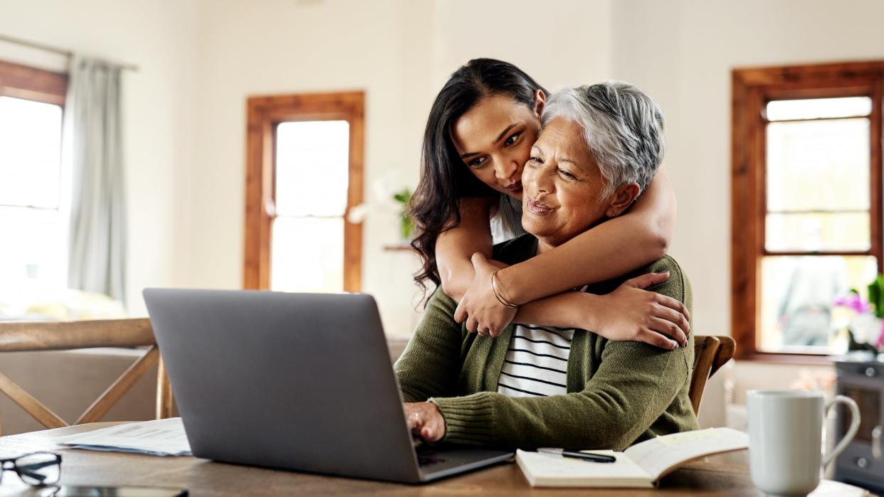 Cropped shot of an attractive young woman hugging her grandmother before helping her with her finances on a laptop.