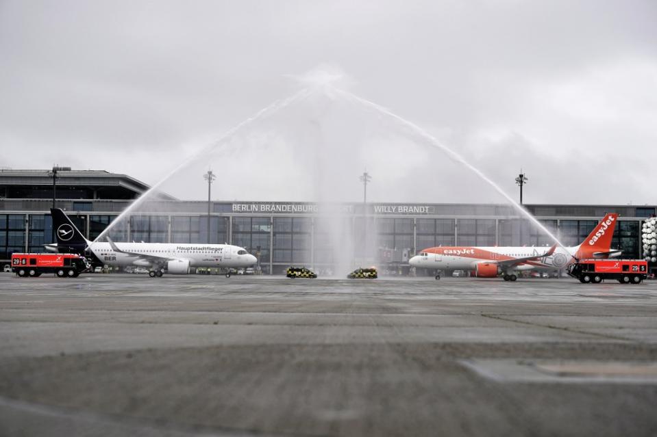 Die ersten beiden Maschinen auf dem BER werden mit einer Wasserfontäne der Flughafen-Feuerwehr auf dem Rollfeld vor Terminal 1 begrüßt.<span class="copyright">Michael Kappeler / dpa</span>