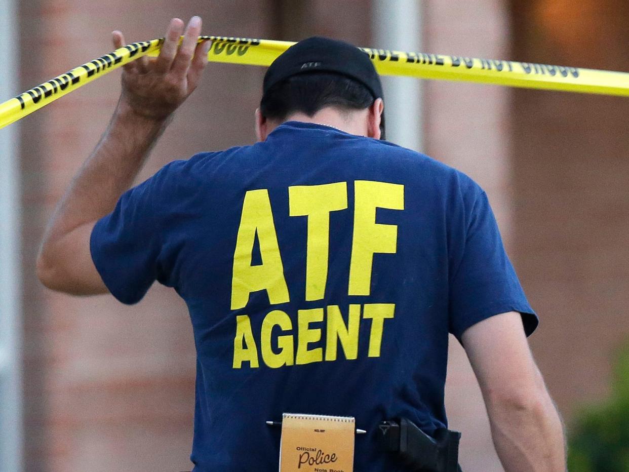 An ATF agent lifts crime scene tape at a scene in DeSoto, Texas in August 2013.