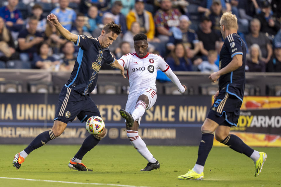 Toronto FC's Derrick Etienne Jr., center, kicks the ball away from Philadelphia Union's Jack Elliott, left, during the first half of an MLS soccer match Wednesday, May 29, 2024, in Chester, Pa. (AP Photo/Chris Szagola)