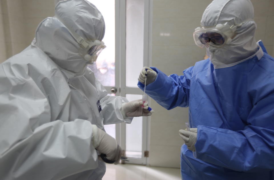 Two medical staff treating coronavirus patients in body suits, face masks and goggles.