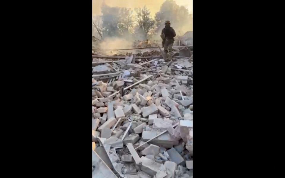 A man wearing military uniform stands on top of rubble in Bilohorivka (via REUTERS)