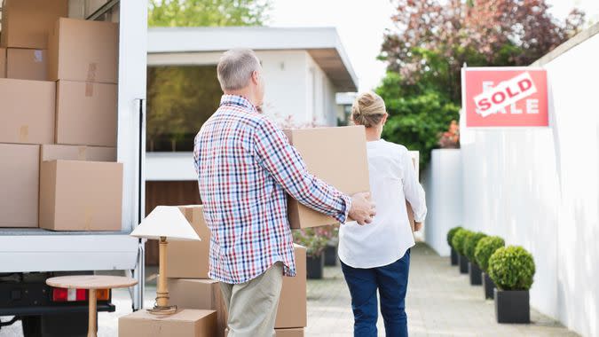 Couple unloading boxes from moving van.