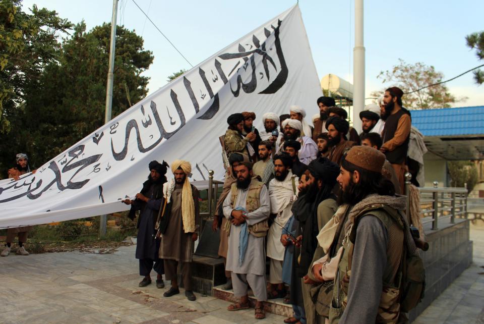 Taliban fighters raise their flag at the Ghazni provincial governor's house in southeastern Afghanistan on Aug. 15.