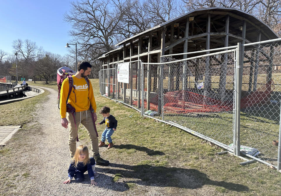 R.J. Tursi and his young children play by part of an artwork, called Greenwood Pond: Double Site, Sunday, Feb. 25, 2024, in Des Moines, Iowa. The Des Moines Arts Center plans to rip out the roughly 30-year-old artwork that lines a pond in a historic city park. The decision to remove the work, made up of a series of walkways, shelters and viewing sites, has outraged arts advocates nationally and surprised local residents. (AP Photo/Scott McFetridge)