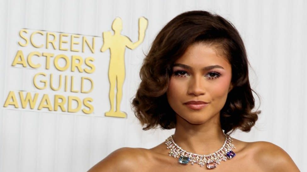 Zendaya with medium-length brown hair wearing a necklace at an award ceremony