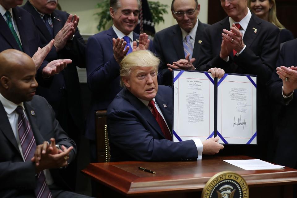 President Trump holds up the Veterans Choice Program And Improvement Act with VA Secretary David Shulkin clapping behind him, center, at the White House on April 19, 2017.