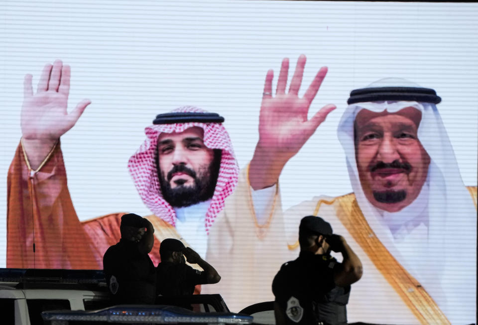 FILE - Saudi special forces salute in front of a screen displaying images Saudi King Salman, right, and Crown Prince Mohammed bin Salman after a military parade in preparation for the annual Hajj pilgrimage, in the Muslim holy city of Mecca, Saudi Arabia, July 3, 2022. President Joe Biden will visit the Middle East this week at a time when the region is experiencing dramatic changes and struggling to address deep problems. He'll become the first U.S. president to travel directly from Israel to Saudi Arabia, a reflection of closer ties between the Jewish state and its Arab neighbors. (AP Photo/Amr Nabil, File)