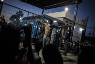 A migrant stands alongside others outside a holding centre for migrants the Spanish North African enclave of Melilla, Spain, Tuesday May 18, 2021. A large group of Africans crossed into Melilla on the North African coast in the early hours by jumping over the enclave's double fence. Spain said around 6,000 people had earlier crossed the border into Spain's other North Africa enclave of Ceuta. (AP Photo/Javier Bernardo)