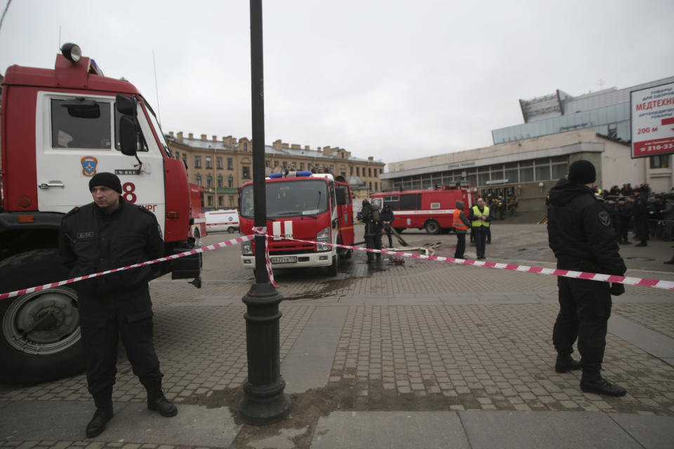 Russian police and emergency service officers stand near fire trucks near the entrance of Sennaya Square subway station in St. Petersburg, Russia, Monday, April 3, 2017. The subway in the Russian city of St. Petersburg is reporting that there are fatalities and several people have been injured in an explosion on a subway train. (AP Photo/Evgenii Kurskov)