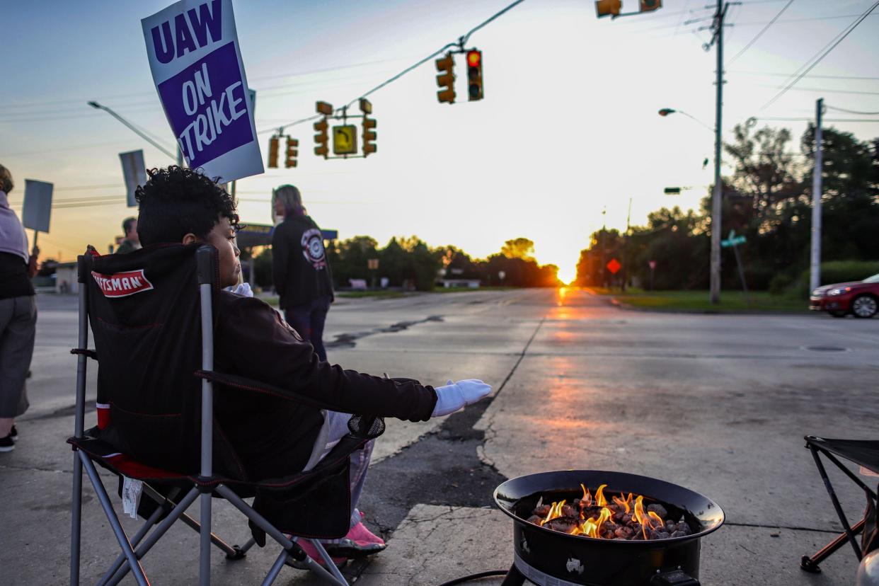 Regina Knuckles, 46, of Flint stays warm next to a fire pit on the fourth day of the nationwide strike of UAW strike against General Motors after stalled contract talks in Flint, Mich. on Thursday, Sept. 19, 2019. 