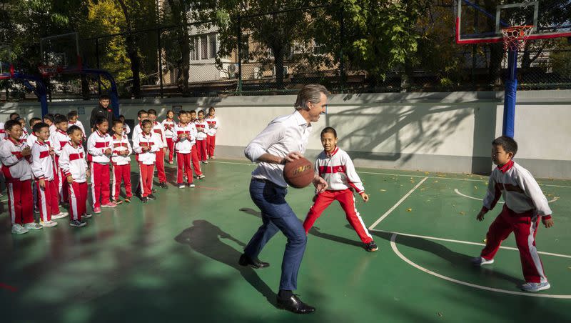 In this photo provided by the Office of the Governor of California, Gov. Gavin Newsom plays basketball with children at a school in Beijing on Friday Oct. 27, 2023.