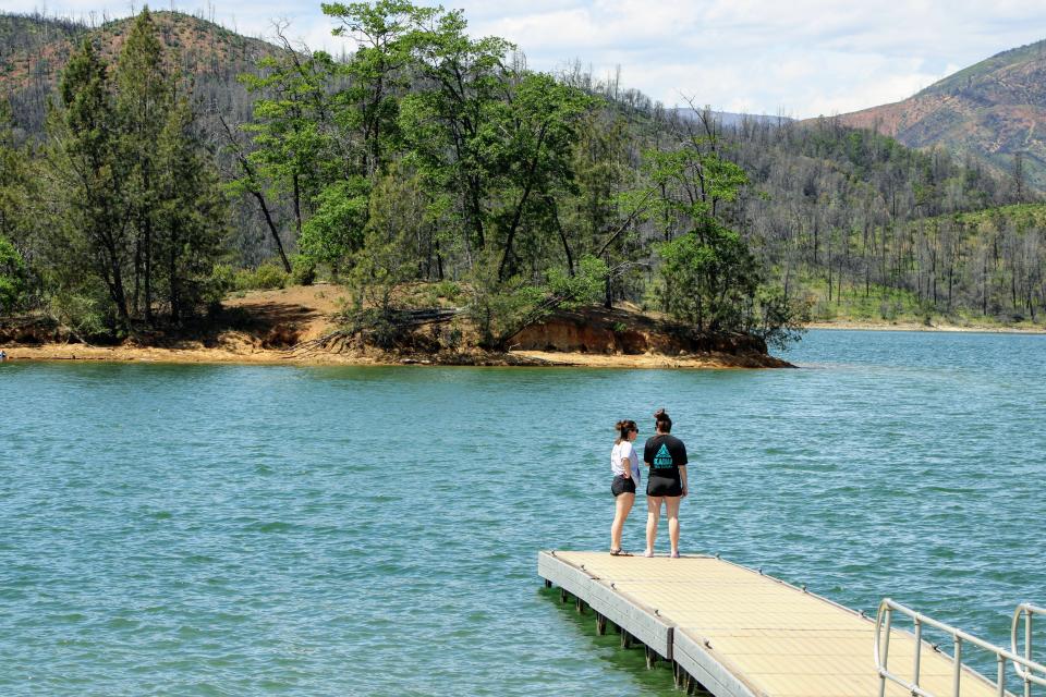 Two women stand on a dock overlooking Whiskeytown Lake near the Brandy Creek boat ramp in April 2020.