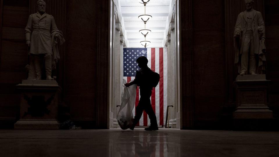 An ATF police officer cleans up debris and personal belongings strewn across the floor of the Rotunda in the early morning hours of Thursday, Jan. 7, 2021, after protesters stormed the Capitol in Washington, on Wednesday.