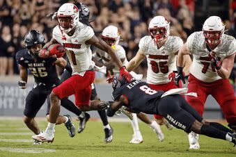 Louisville's Jamari Thrash (1) slips the tackle of North Carolina State's Robert Kennedy (8) during the second half of an NCAA college football game in Raleigh, N.C., Friday, Sept. 29, 2023. (AP Photo/Karl B DeBlaker)