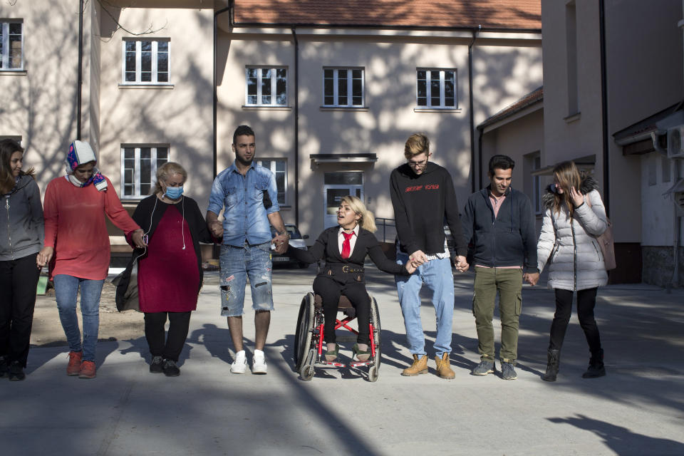 In this photo taken Tuesday, Nov. 13, 2018, Mahana Jami, 34, center, dances with friends inside a government run camp for refugees and migrants in Bosilegrad, some 250 kilometers southeast of Belgrade, Serbia. As a little girl in a wheelchair in Iran, Jami used to watch other children play on a slide and wondered why she couldn't do the same. She then made a promise to herself to always dream big and never let her disability stand in the way. (AP Photo/Marko Drobnjakovic)