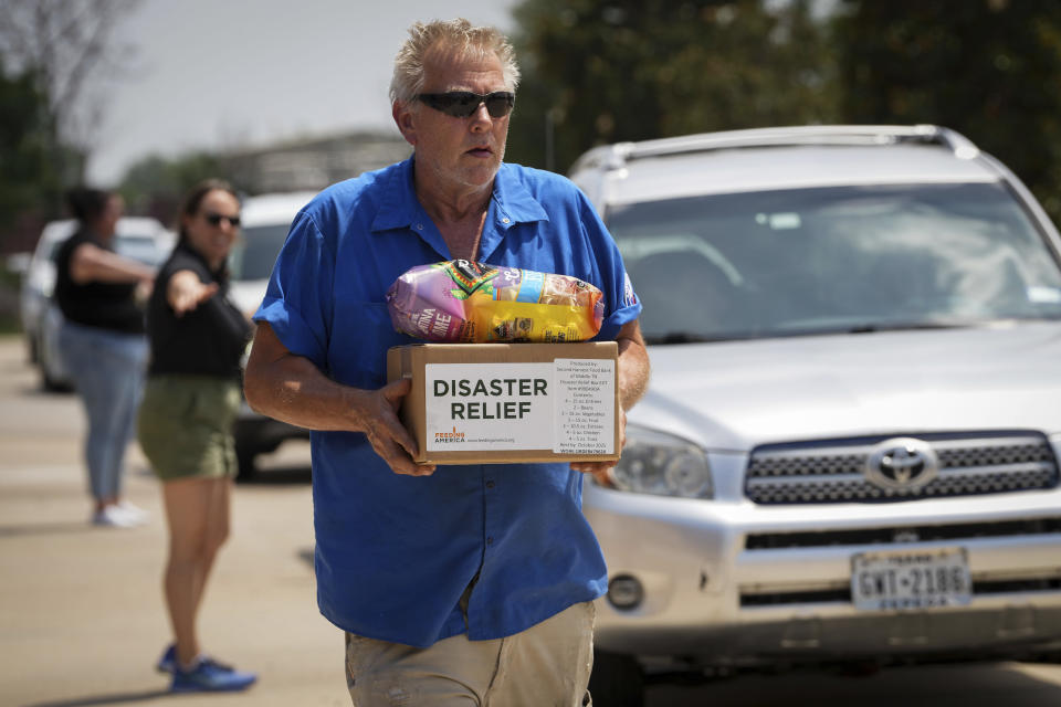 Andrew Hallard, a mechanic with Harris County Precinct 4, works through the heat to distribute food and water in the aftermath of a destructive storm Saturday, May 18, 2024, at the Richard and Meg Weekley Community Center in Cypress. Texas. (Jon Shapley/Houston Chronicle via AP)