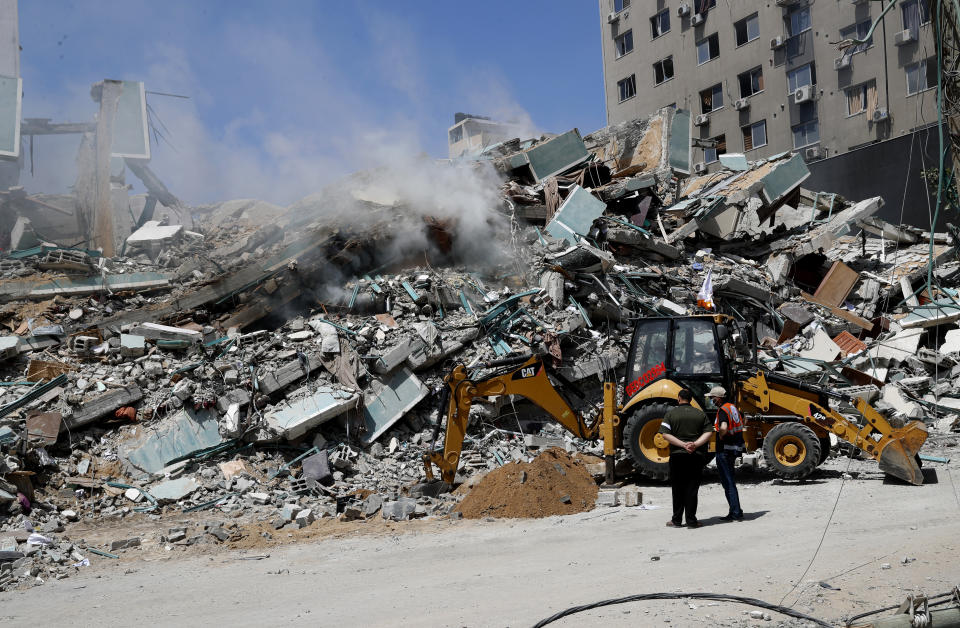 Workers clear rubble from a building that was destroyed by an Israeli airstrike on Saturday that housed The Associated Press, broadcaster Al-Jazeera and other media outlets, in Gaza City, Sunday, May 16, 2021. (AP Photo/Adel Hana)