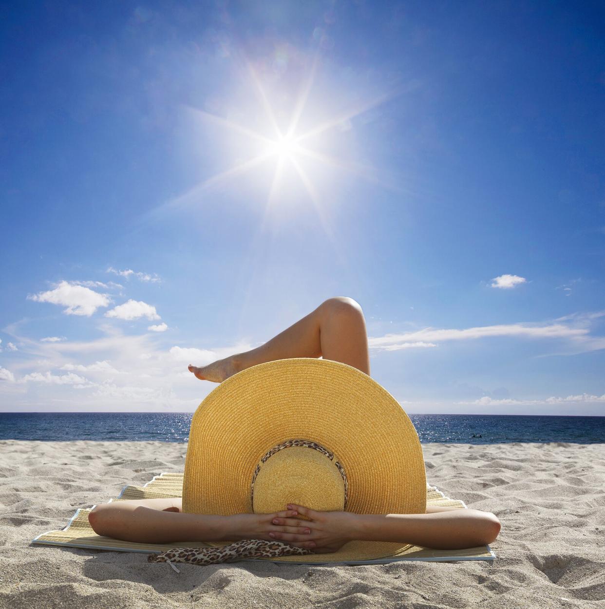 Woman in straw hat sunbathing on beach