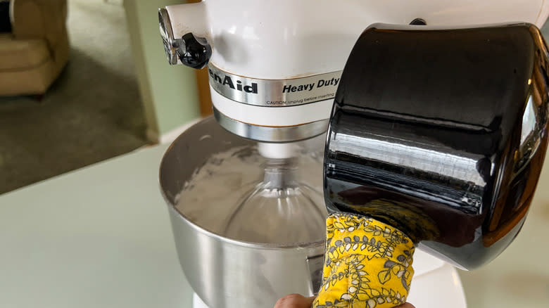 Pouring hot sugar syrup from saucepan into whipped egg whites in stand mixer