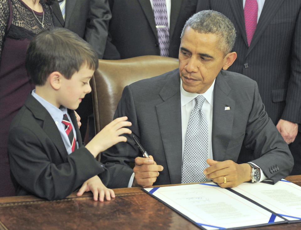 Obama presents a pen to Jacob Miller after signing legislation. (Photo: Pool via Getty Images)