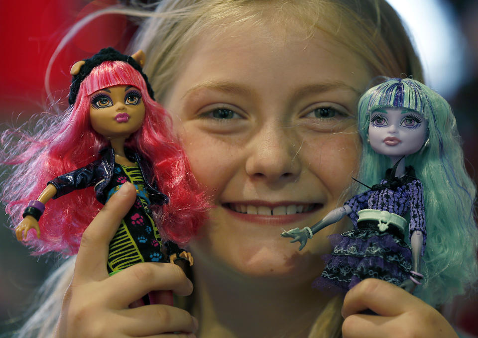 In this Thursday, June 27, 2013, photo,Tegan, 9, poses with Monster High Dolls as part of a Christmas toy preview at the toy store Hamleys in London. Mattel’s Monster High Dolls, with neon hair and punk clothing, have grown to an estimated $500 million in annual sales since debuting in 2010. (AP Photo/Frank Augstein)