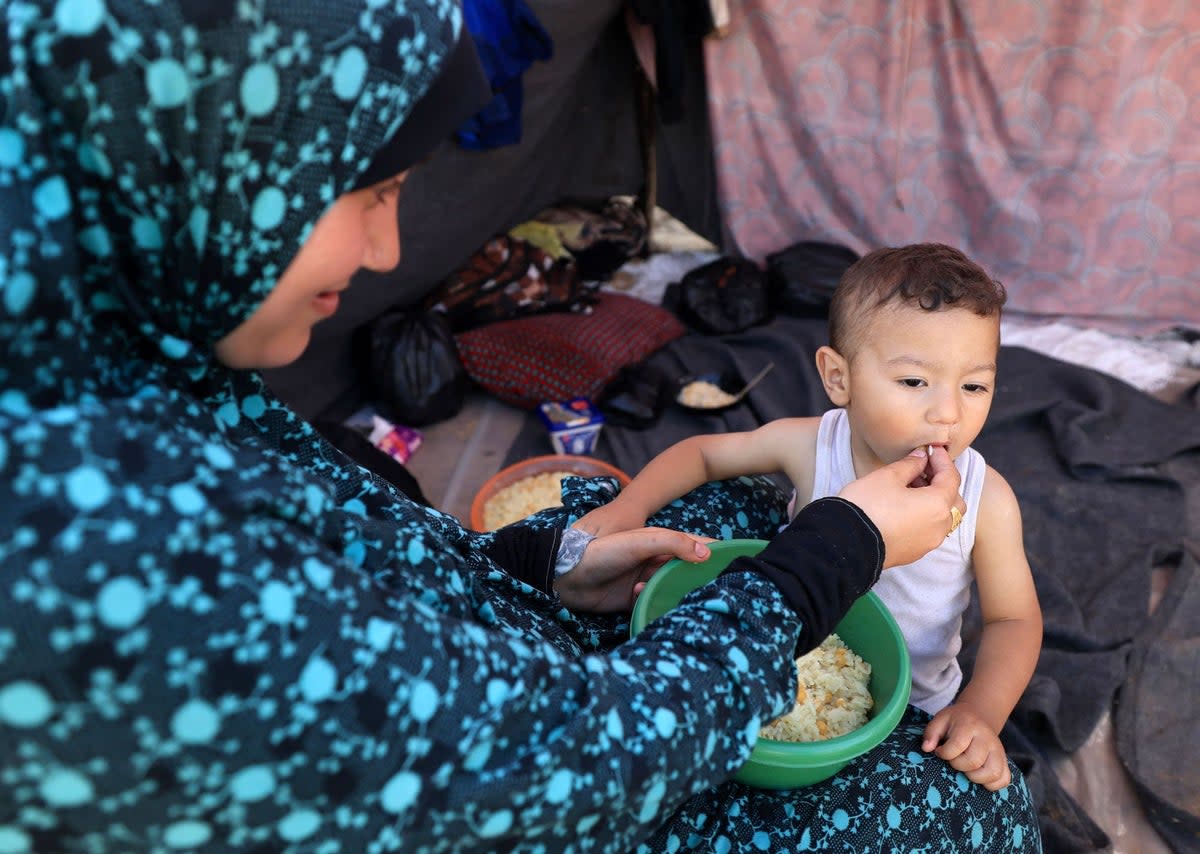 A woman feeds a baby at a makeshift camp for displaced people in Khan Yunis in southern Gaza (AFP via Getty Images)