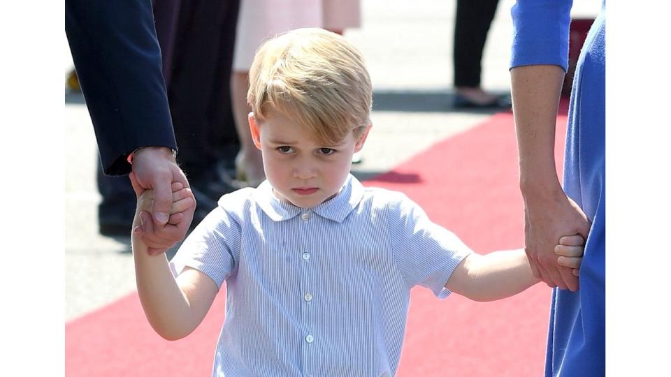 A young Prince George holding the hands of Prince William and Kate Middleton