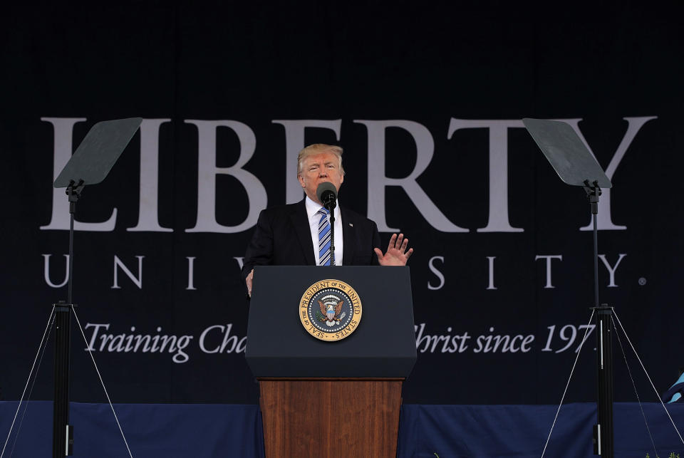 Donald Trump stands at a podium. Behind him is a Liberty University banner.