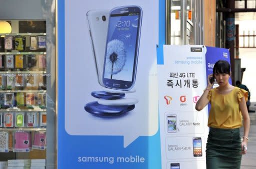 A woman walks past a signboard (C) of Samsung Galaxy S3 at a mobile phone shop in Seoul on August 27, 2012. Samsung sought Monday to rally employees after a $1.05 billion US court judgment in favour of arch-rival Apple pushed its shares sharply lower amid fears about the fallout in the key American market