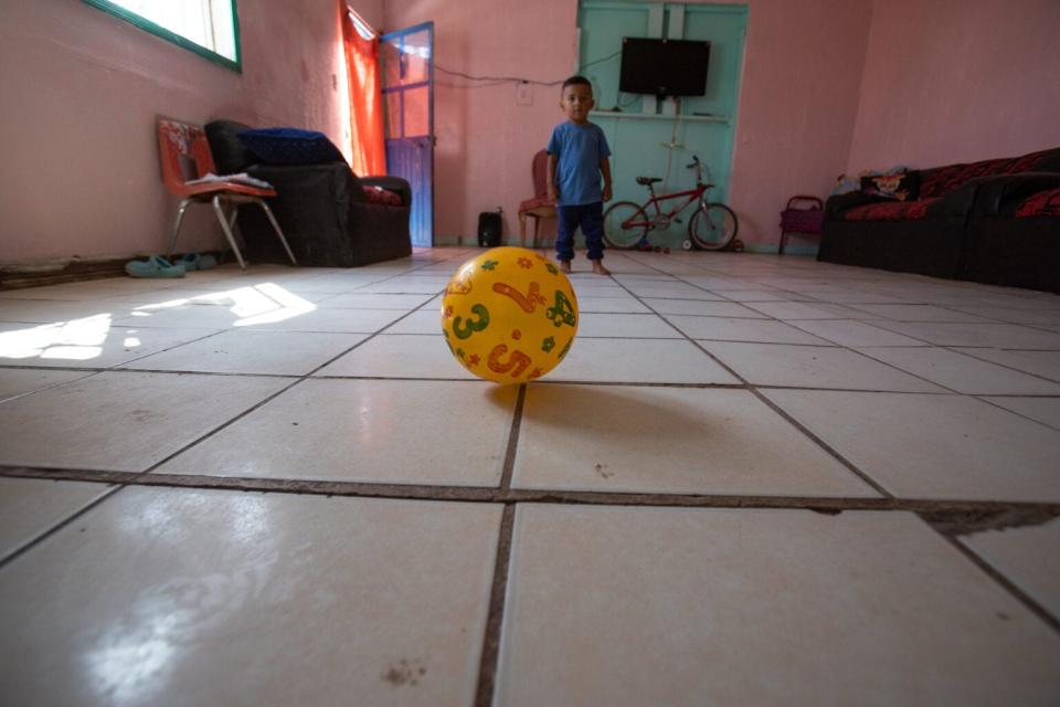 A 3-year-old Honduran boy chases after a ball in the migrant shelter where he stays with his family.