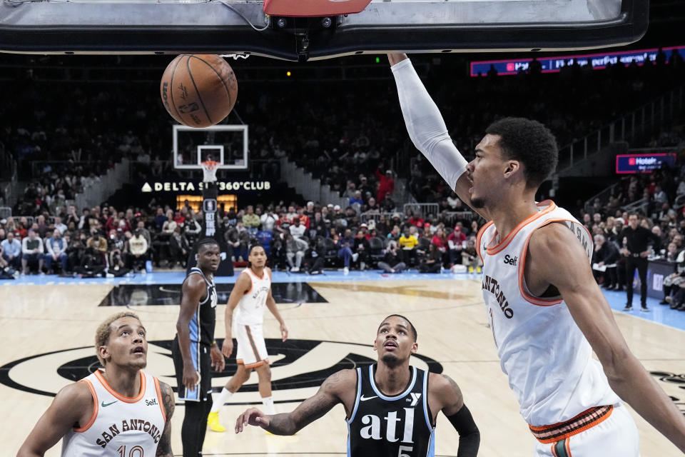 San Antonio Spurs center Victor Wembanyama (1) scores as Atlanta Hawks guard Dejounte Murray (5) and Spurs forward Jeremy Sochan (10) looks on during the second half of an NBA basketball game Monday, Jan. 15, 2024, in Atlanta. (AP Photo/John Bazemore)