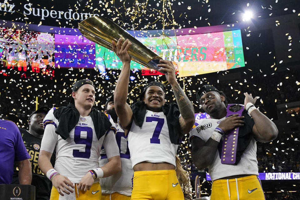 LSU safety Grant Delpit holds the trophy as quarterback Joe Burrow, left, and linebacker Patrick Queen look on after a NCAA College Football Playoff national championship game against Clemson, Monday, Jan. 13, 2020, in New Orleans. LSU won 42-25. (AP Photo/David J. Phillip)