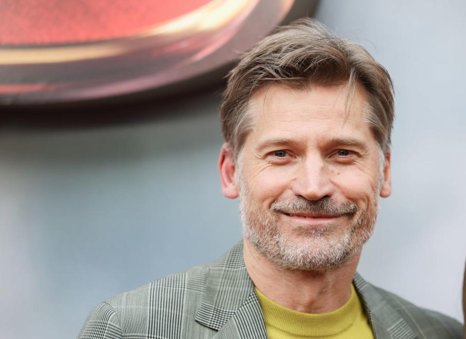 a close up of nikolaj coster waldau wearing a checkered grey suit with a mustard top