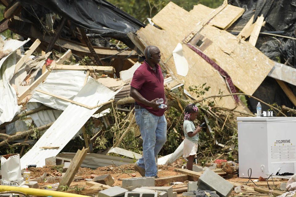 Residents and family members walk past the remains of a mobile home following an overnight tornado that swept through Louin, Miss., Monday, June 19, 2023. (AP Photo/Rogelio V. Solis)