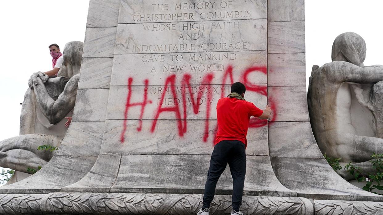 man spraypainting "Hamas" tag on statue outside Union Station in Washington, D.C.