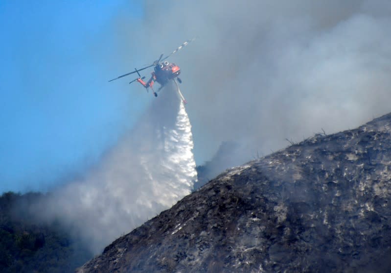 Firefighters battle a blaze from the air that was threatening homes in the Pacific Palisades community of Los Angeles