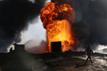 Thick smoke rises from a fire which broke out at oil wells set ablaze by Islamic State militants before fleeing the oil-producing region of Qayyara, Iraq, January 18, 2017. Picture taken January 18, 2017. REUTERS/Girish Gupta