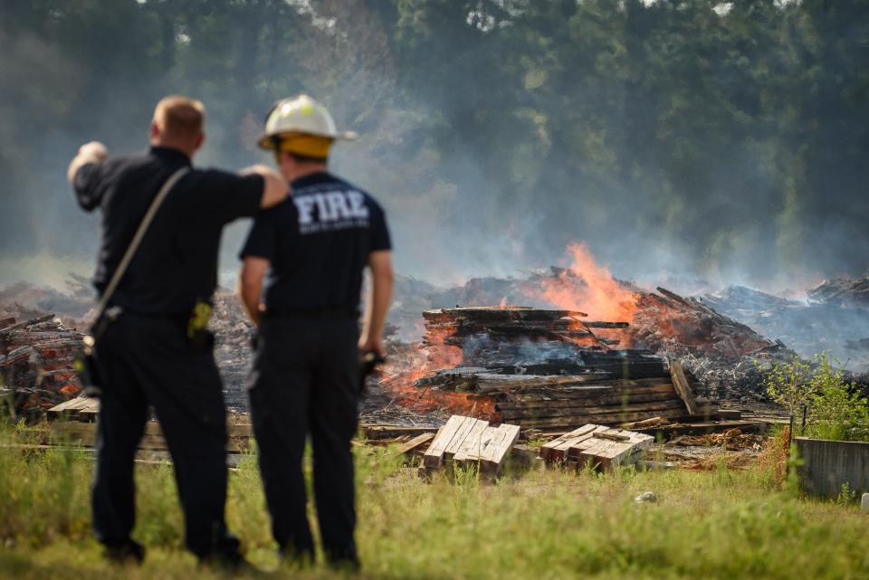 Fayetteville firefighters work a fire at a large pile area of railroad ties along Shaw Mill Road on Monday, Aug. 21, 2023.