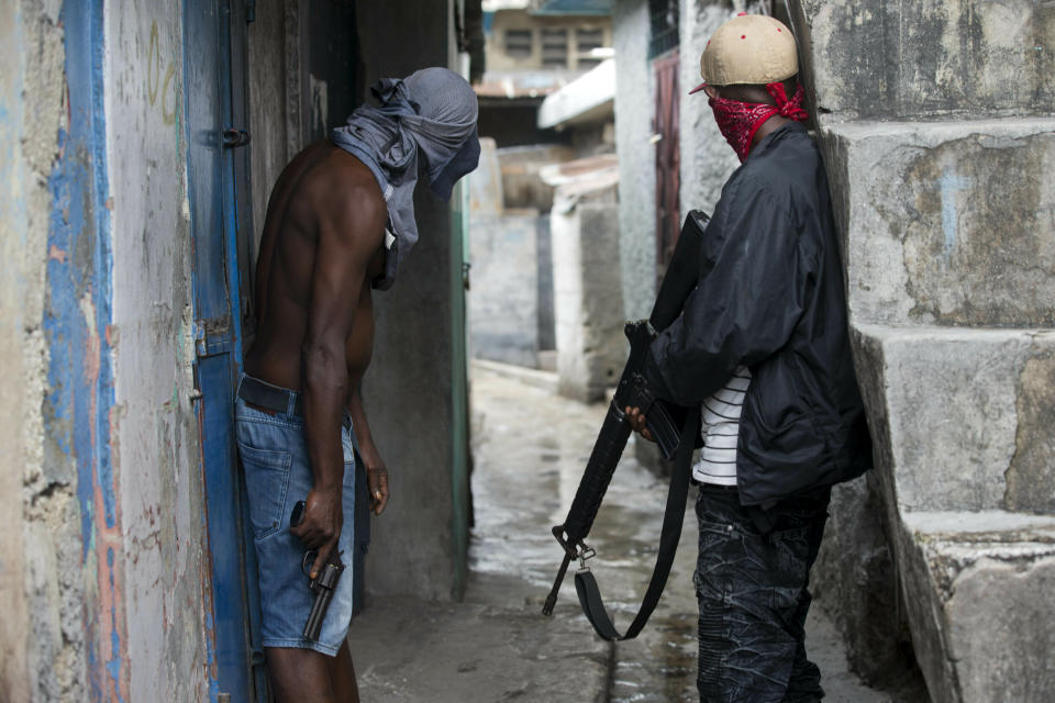 In this May 31, 2019, photo, gang members stand guard and hold guns six months after a massacre in the La Saline slum of Port-au-Prince, Haiti. “Gangs are multiplying because the government is weak,” said Paul Eronce Villard, Haiti’s general prosecutor, who estimates there are more than 50 gangs now operating in the country. “It’s a real challenge for police.” (AP Photo/Dieu Nalio Chery)