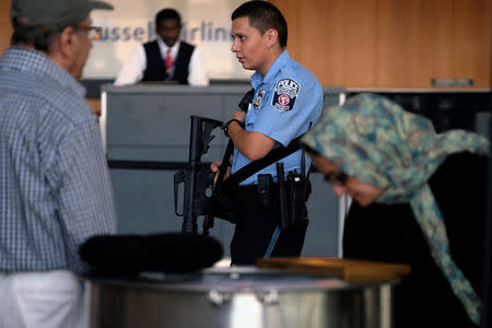 A police officer patrols with a rifle as passengers gather their luggage at Dulles International Airport in Dulles, Virginia, U.S. September 24, 2017. REUTERS/James Lawler Duggan