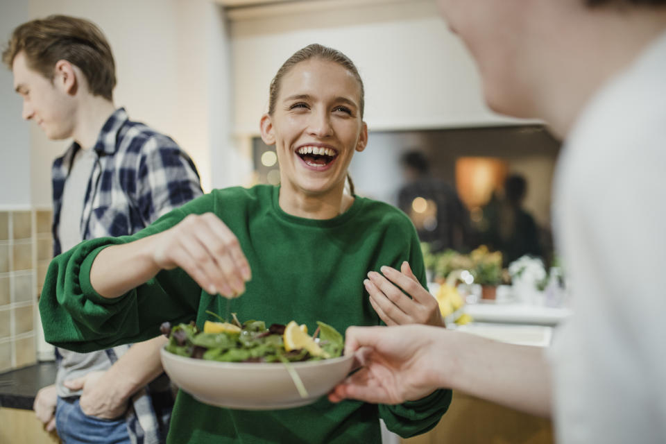 Woman serving dinner with her friends. (Getty Images)