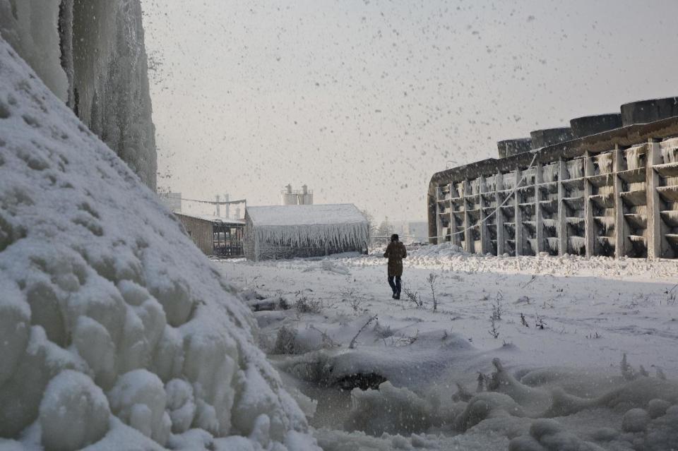 An employee of Kosovo's main power plant "Kosovo A" walks beside cooling towers engulfed on ice in the town of Obilic on Wednesday, Jan 11, 2017. As temperatures plummeted to -25 C (-13 F), there were power outages in many areas in what meteorologists said was the coldest weather since 1963, when it dropped to -32.5 Centigrade (-26.5 Fahrenheit) in the eastern Kosovo city of Gjilan. (AP Photo/Visar Kryeziu)