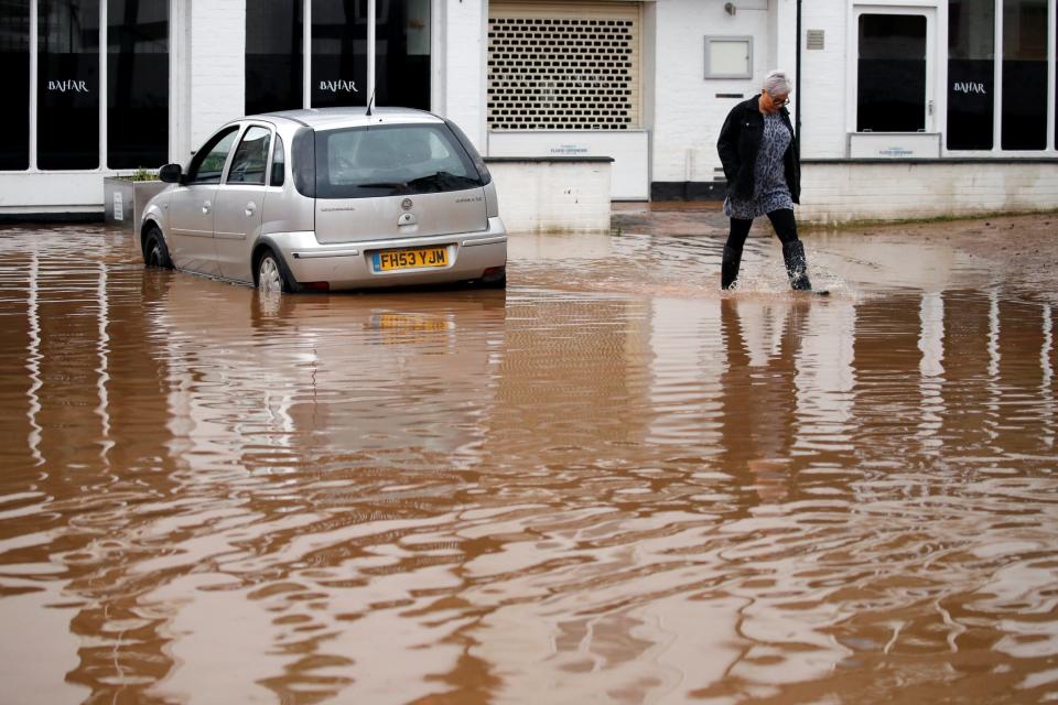 A woman wades through flood water after Storm Dennis in Tenbury Wells (REUTERS)